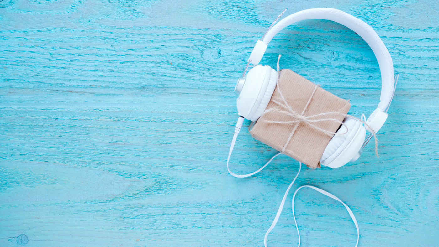 Headphones with a wrapped gift on a teal wooden background
